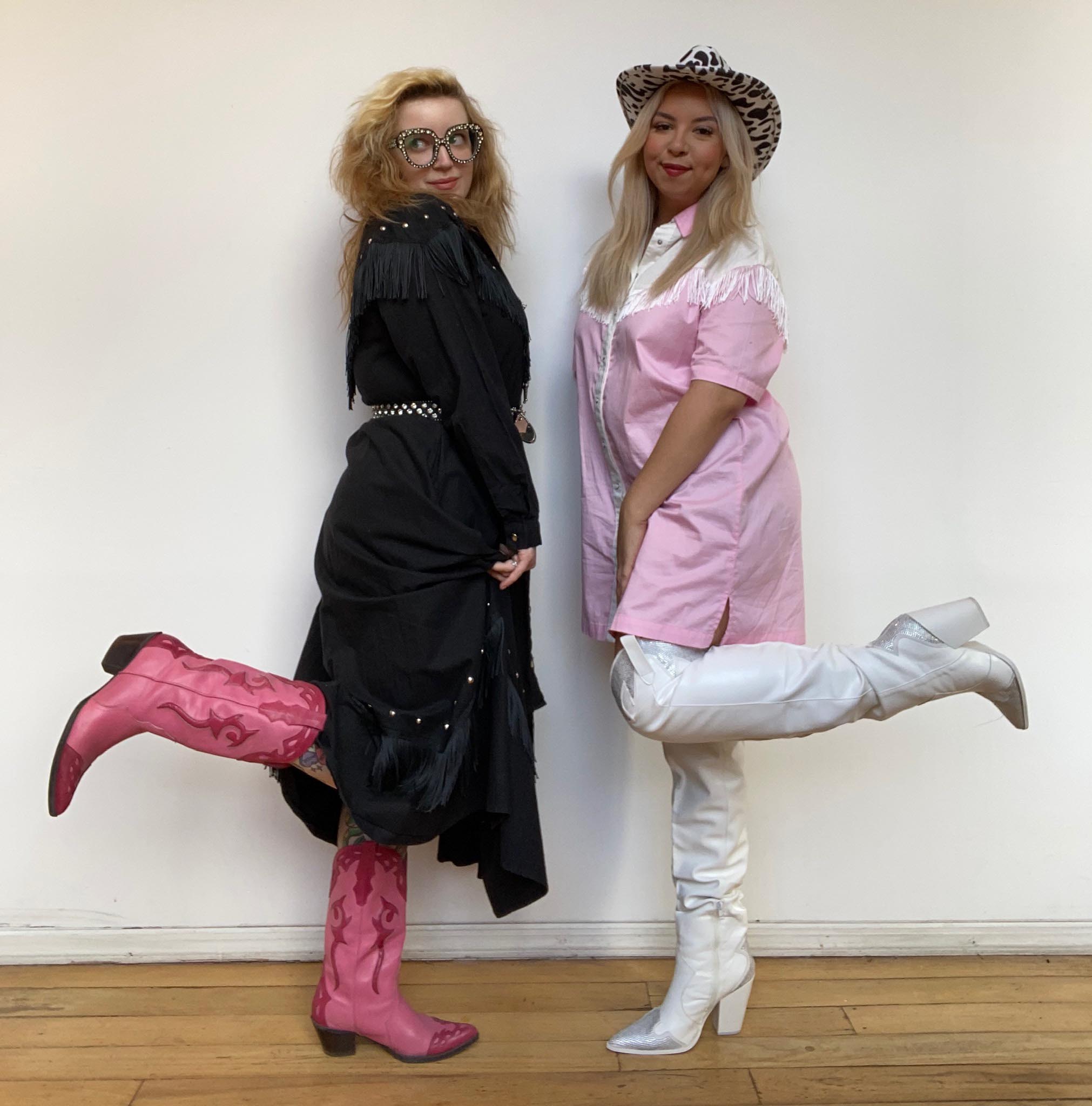 2 women standing against white wall indoors wearing cowboy boots and Western dresses with fring