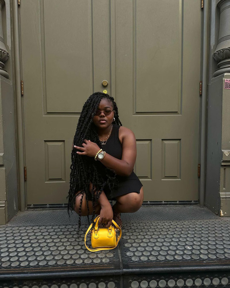 Customer @tinaashanti wearing a black mini dress, gold necklaces, a gold watch, and a bright yellow mini purse. @tinaashanti wearing a black mini dress, gold necklaces, a gold watch, and a bright yellow mini purse