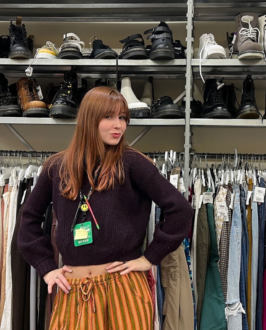 Buffalo Exchange employee in front of clothing rack