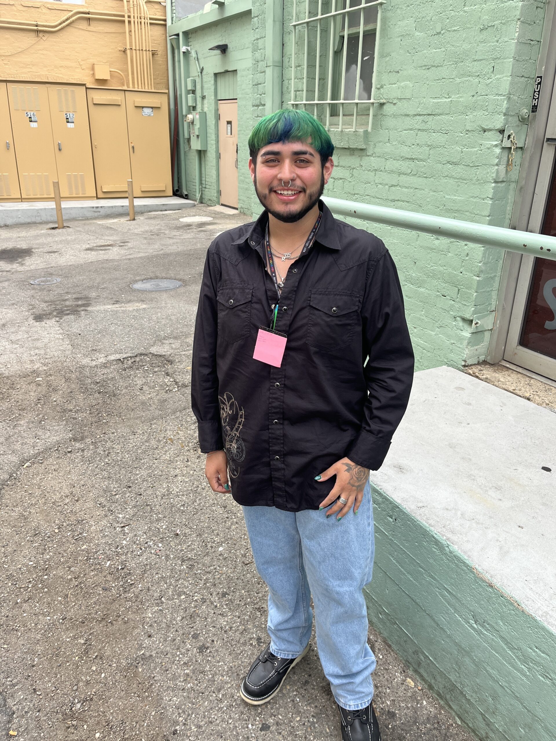 Employee Roman standing outside next to green brick wall